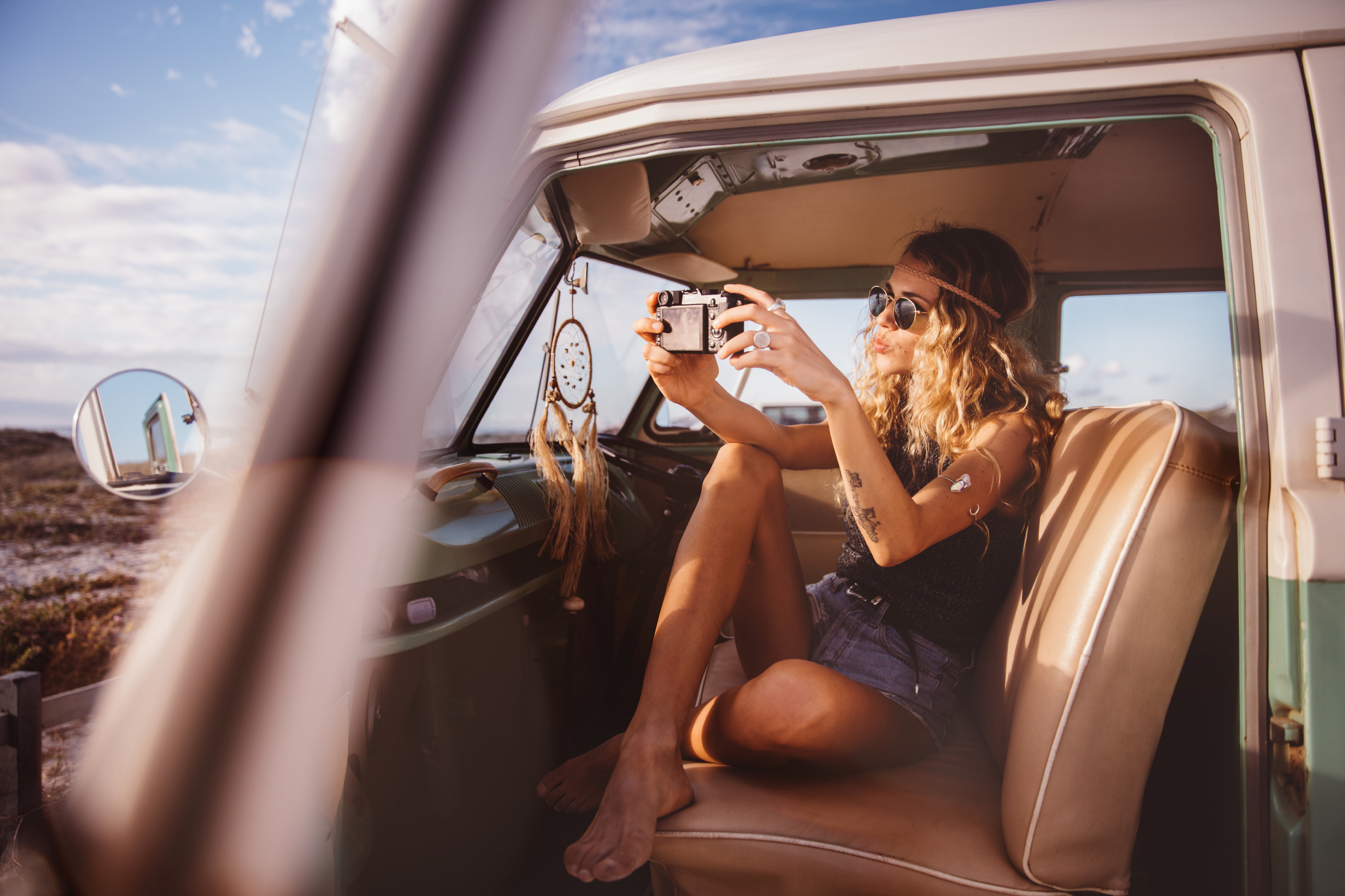 Boho girl in vintage van taking road trip selfie